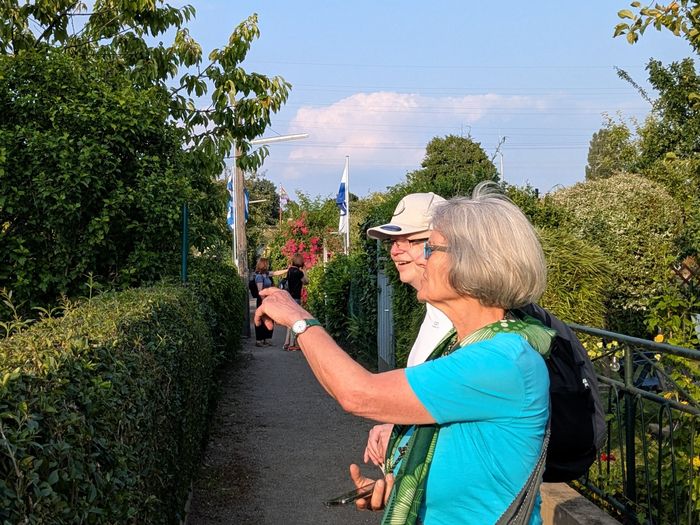 Frau mit Gruppe bei dem Gang durch den Schrebergarten