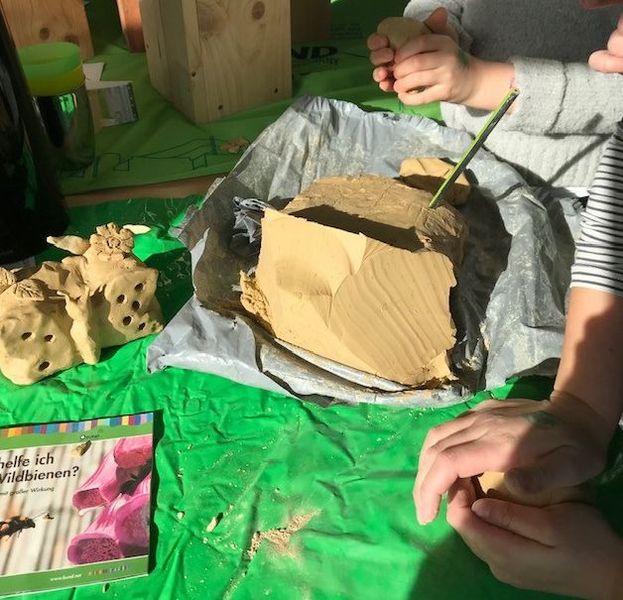Kinder formen eine Nisthilfe mit Löchern für Wildbienen aus Ton